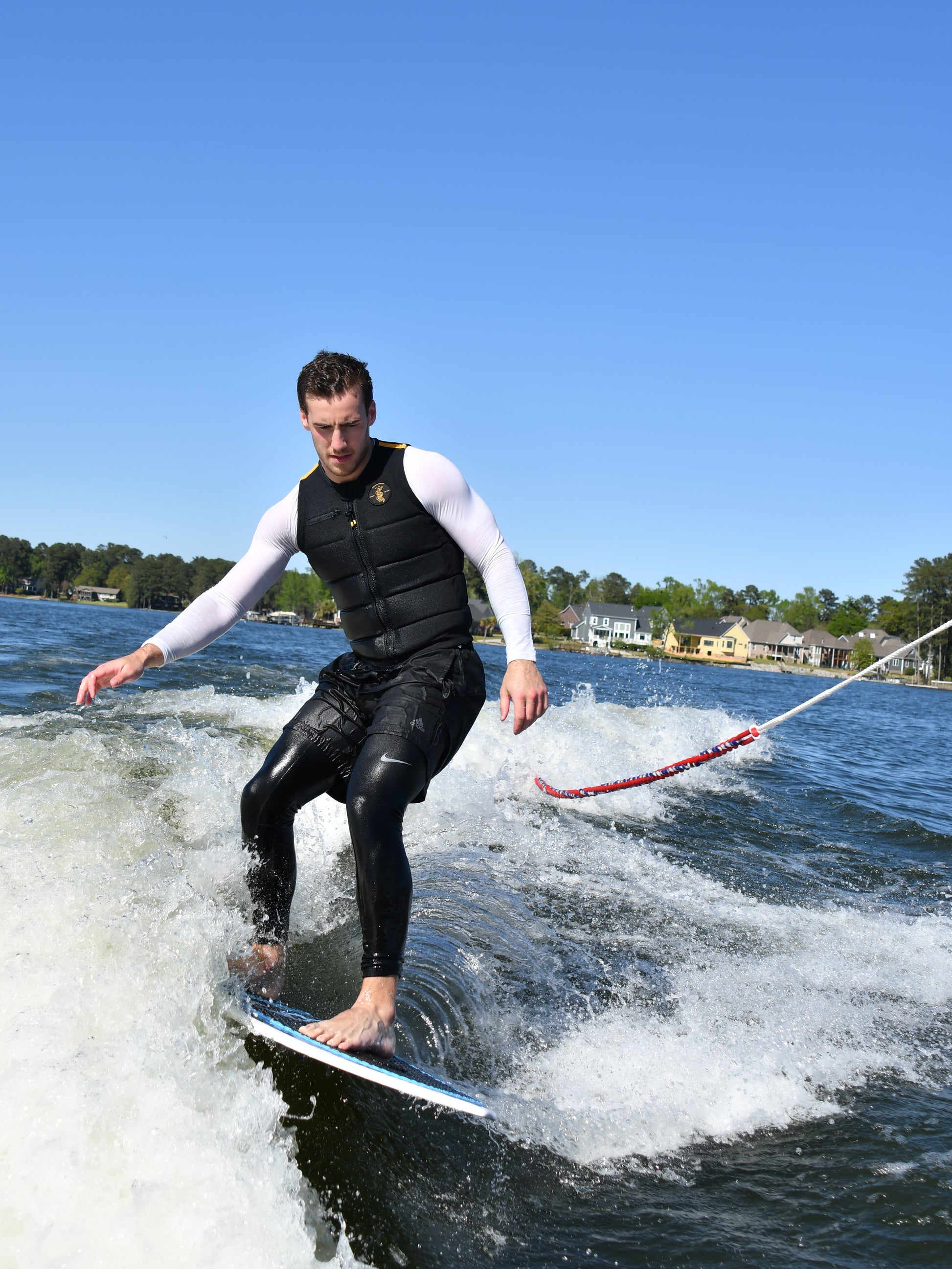 A man wake surfing on a wave behind a watersports boat